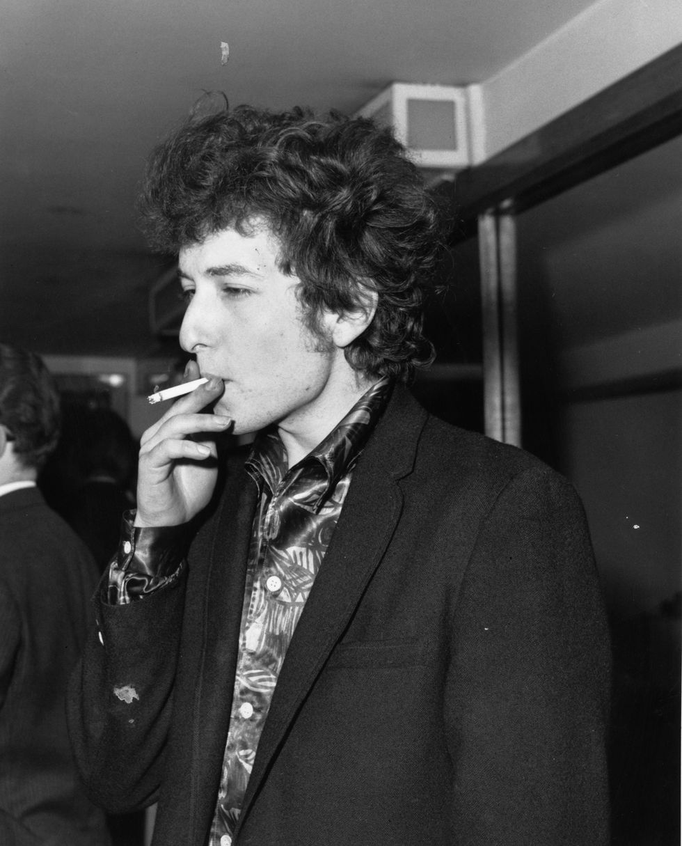 27th April 1965: American singer-songwriter Bob Dylan, whose real name is Robert Zimmerman, smoking a cigarette at The Savoy hotel in London