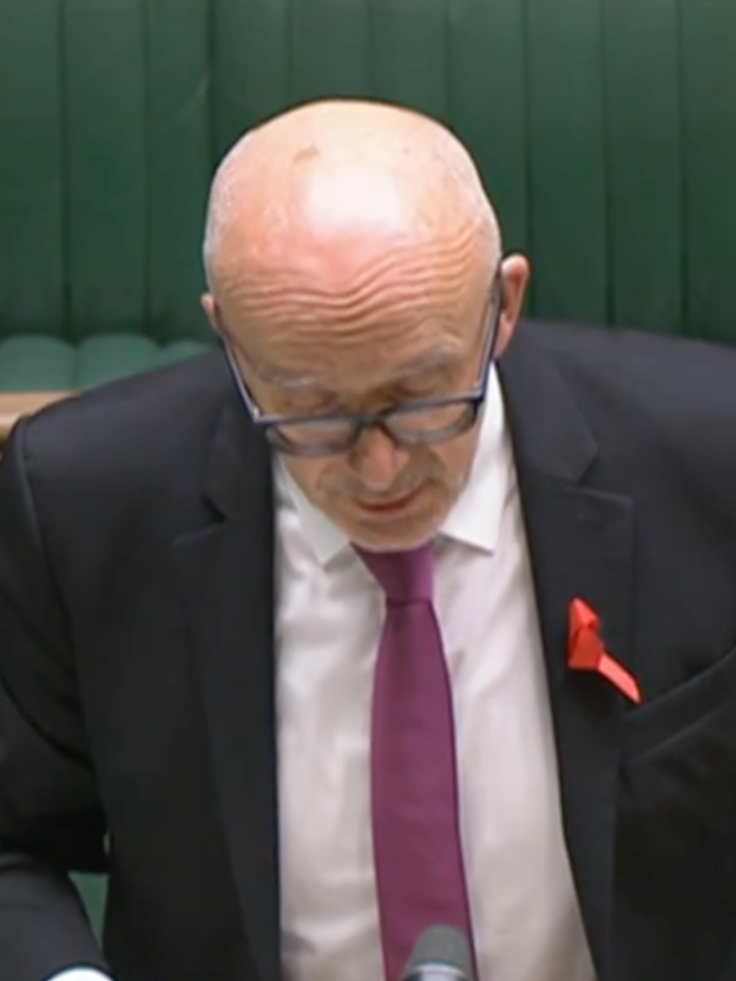 A bald white man with glasses and a black suit stands at the dispatch box in the Commons.