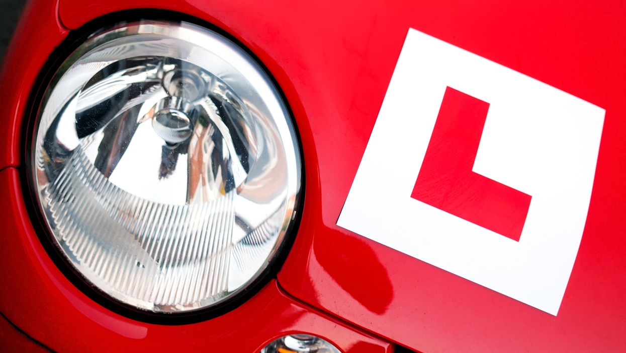 A bonnet and headlight from a red car, with an 'L' plate affixed to it.