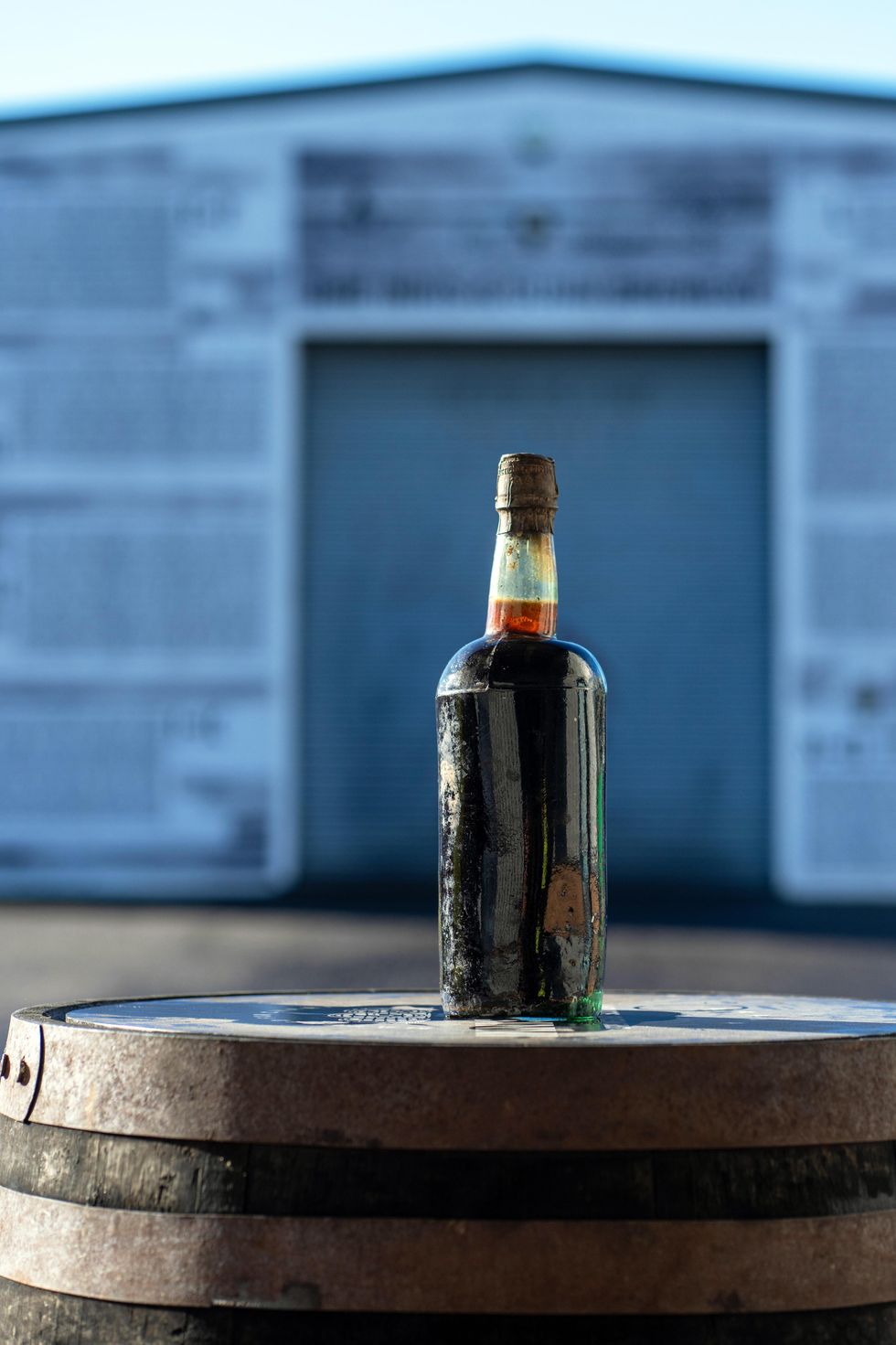 A bottle of beer on top of a wooden barrel