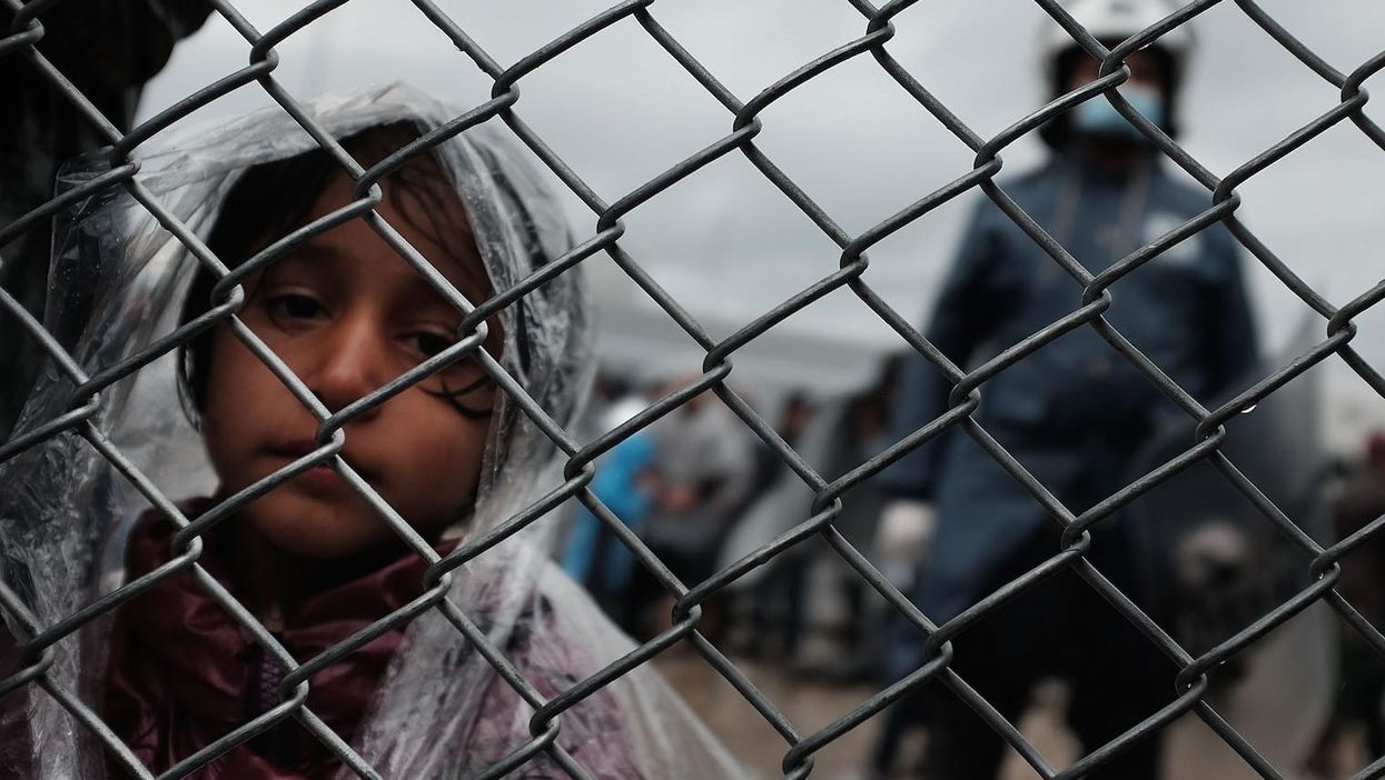 A child waits with her father at the migrant processing center at the increasingly overwhelmed Moria camp on the island of Lesbos