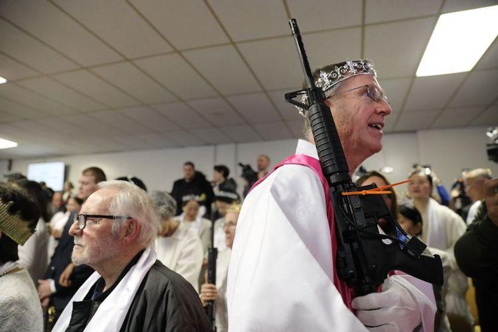 A church offical holds an AR-15 rifle  during a ceremony at the World Peace and Unification Sanctuary in Newfoundland, Pennsylvania