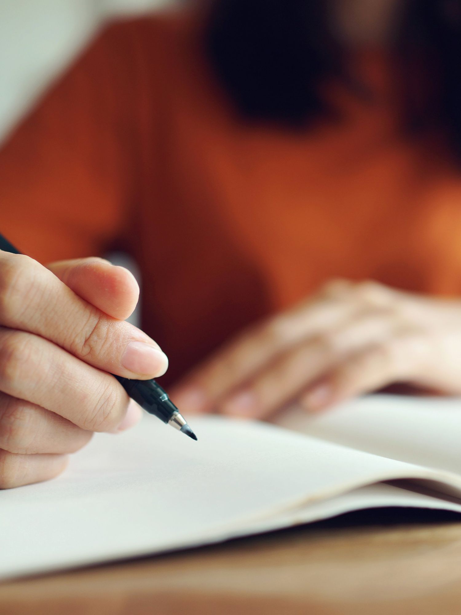 A close-up photo of a woman writing in a notebook.