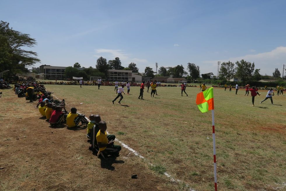 A completed football pitch in Kenya with children playing on it
