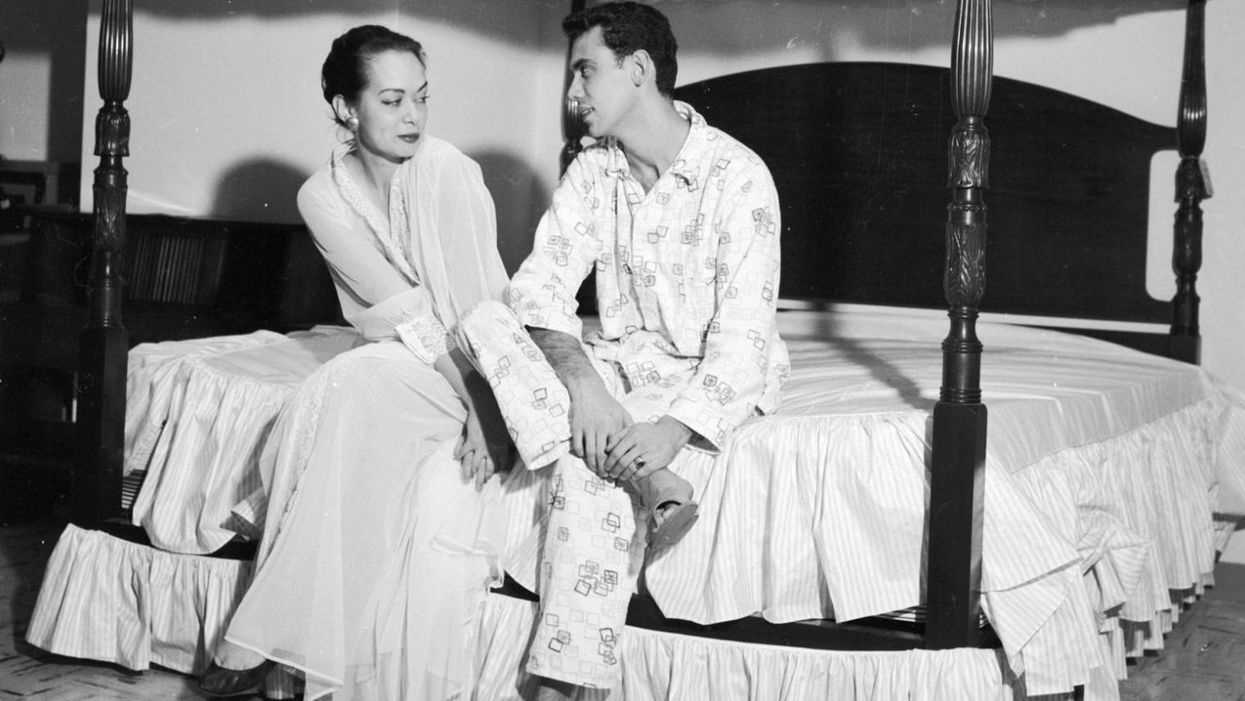 A couple sitting on a specially designed four poster bed, c. 1956