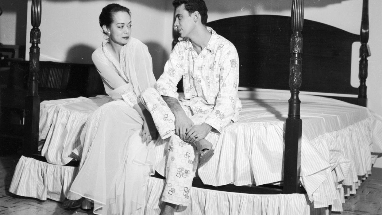 A couple sitting on a specially designed four poster bed, c. 1956