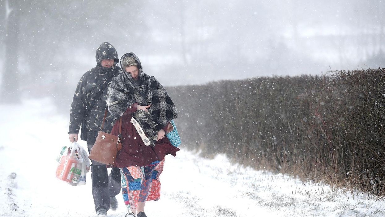 A couple walk along the A53 Buxton Road, which is closed due to heavy snow fall, after abandoning their car near Leek