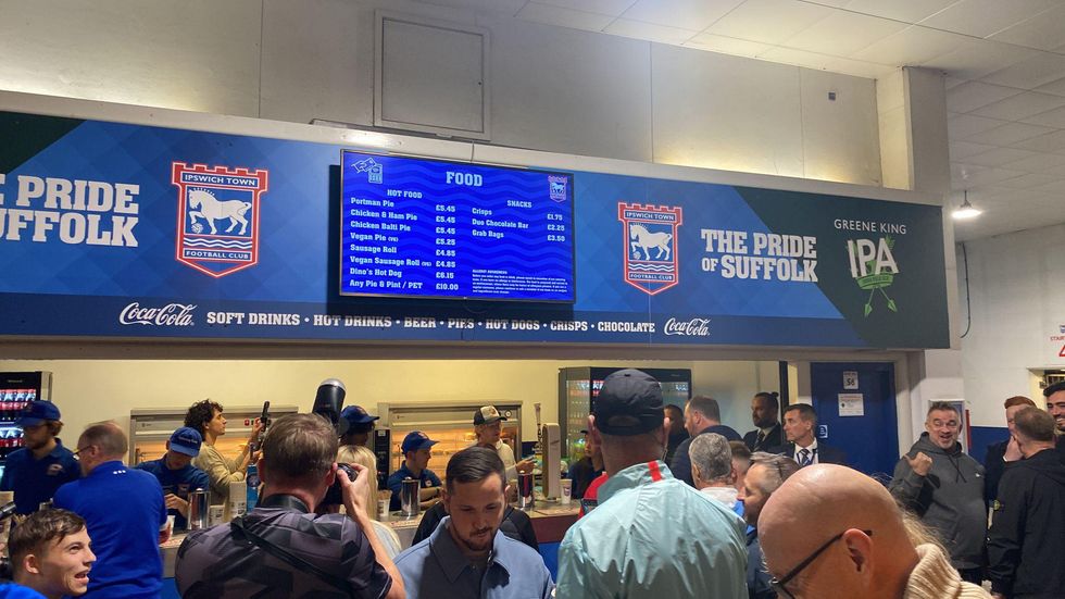 A crowd gathered around the bar at the stadium as Ed Sheeran pours pints for punters