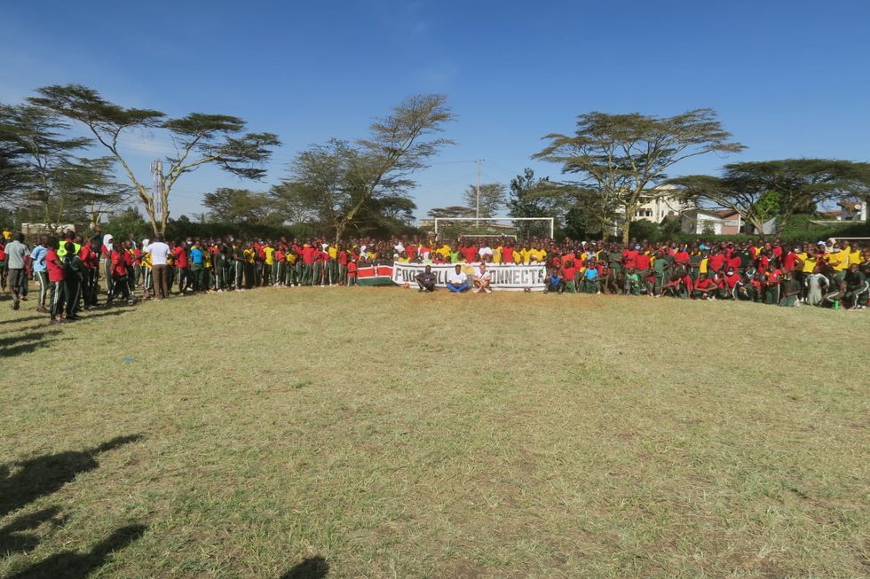 A crowd of people on the completed football pitch in Kenya