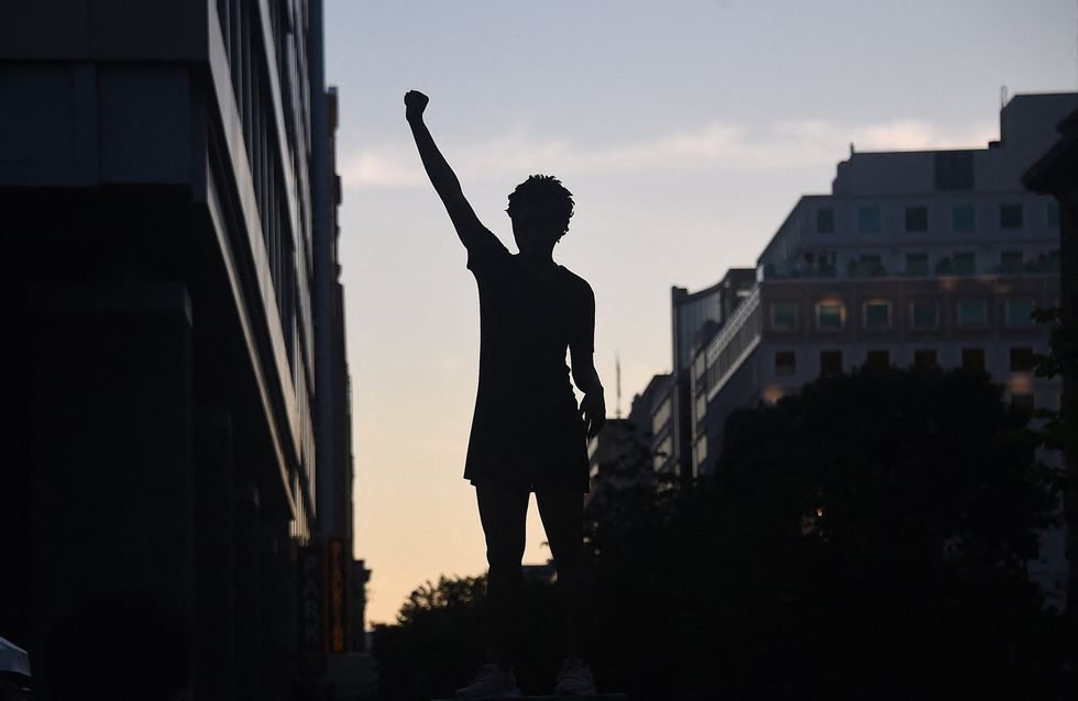 A demonstrator's silhouette is seen as they raise a fist during a protest against police brutality and the death of George Floyd, near the White House on June 7, 2020 in Washington, DC
