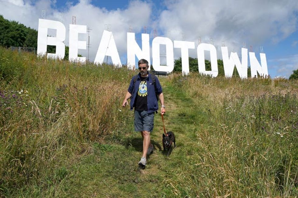 A dogwalker passes the giant sign