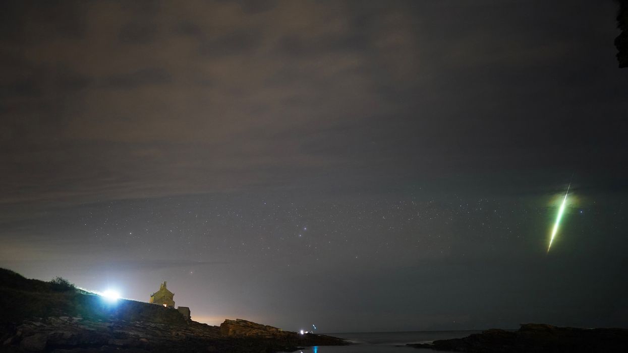 A fisherman watches a meteor during the Draconid meteor shower over Howick rocks in Northumberland ((Owen Humphreys/PA)