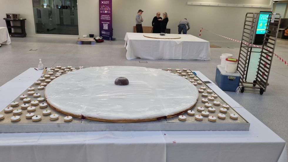 A giant Empire biscuit on a table, surrounded by dozens of smaller versions