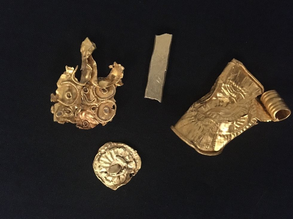 A gold bracteate, which is a type of stamped pendant, a small gold bar, and two other pieces of gold which were probably parts of larger items of jewellery (British Museum/PA)