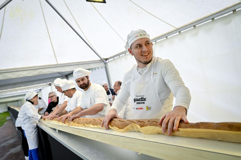 A group of bakers standing around the baguette