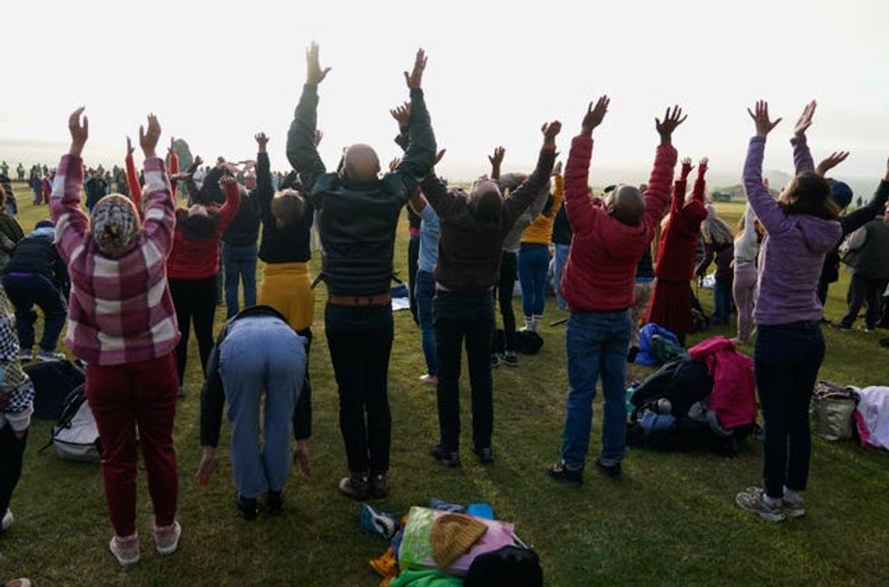 A group of people take part in a yoga session during the summer solstice (Andrew Matthews/PA)