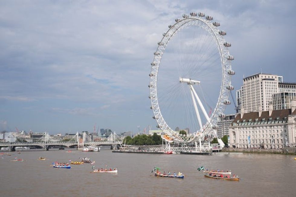 A group of small boats pass the London Eye wheel