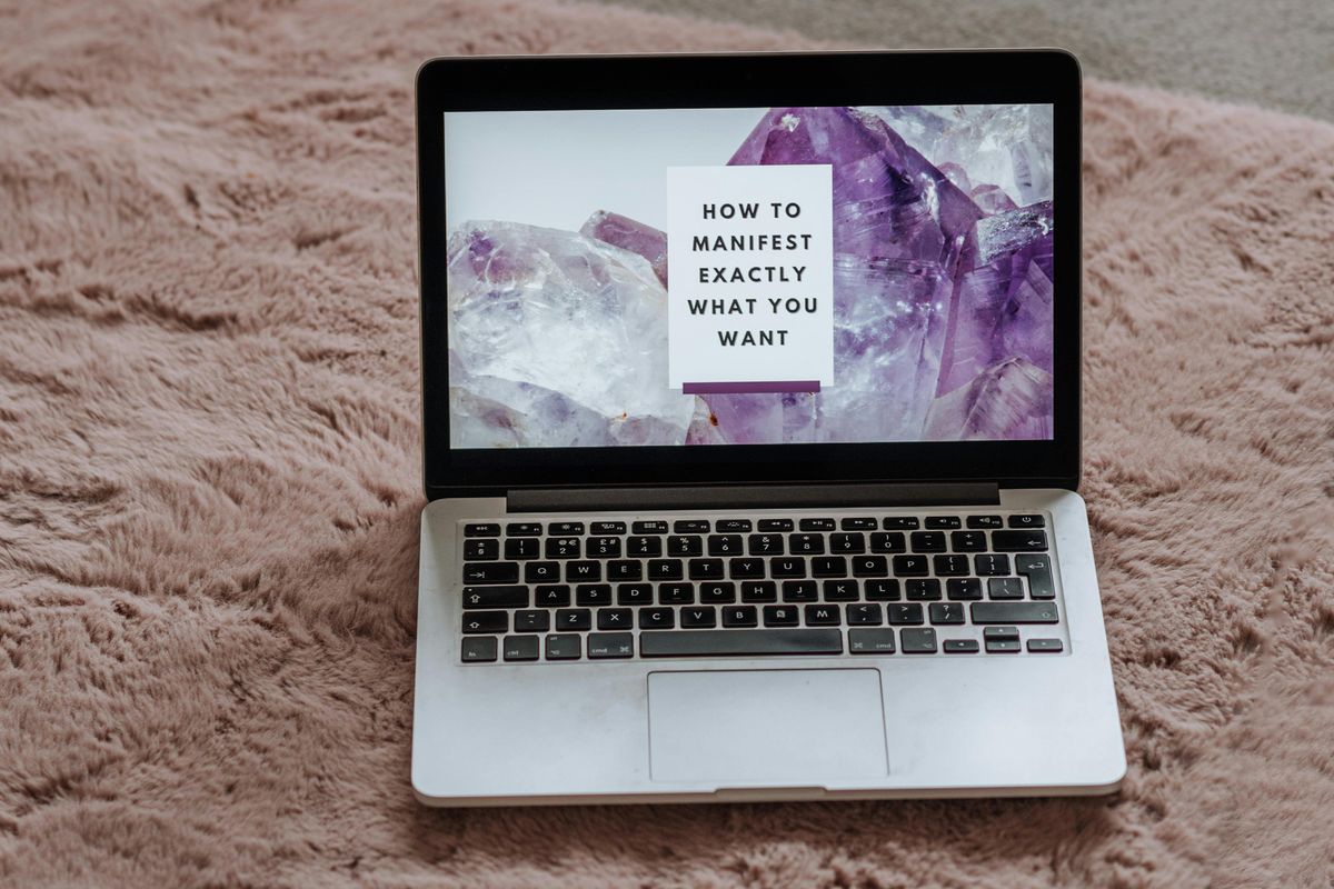 A laptop with the screen reading 'how to manifest exactly what you want'