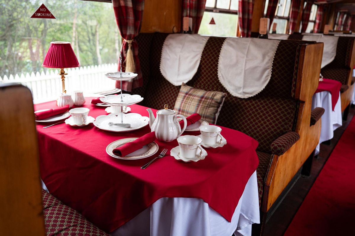 A look inside the train used in The Traitors. It has a red and brown interior with the table set up for afternoon tea.