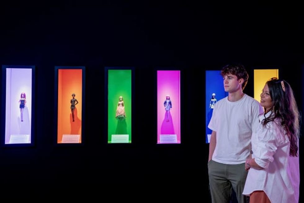 A man and woman look at a Barbie exhibition