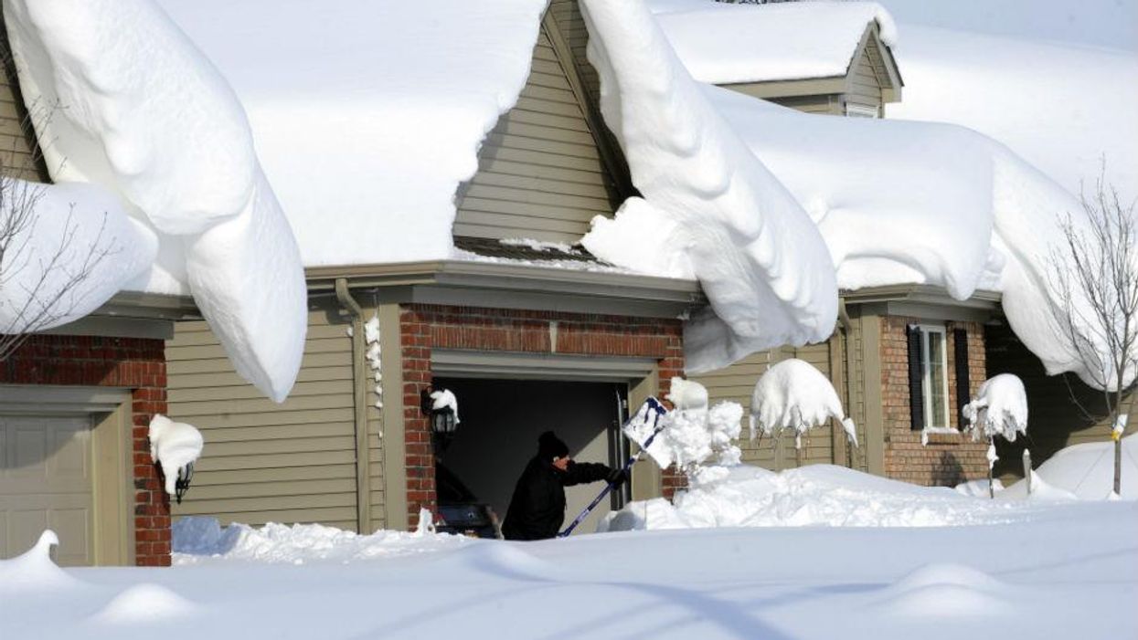 A man attempts to clear snow from his driveway in Lancaster, NY