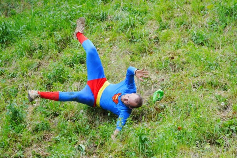 A man in a superman costume falling down Cooper's Hill