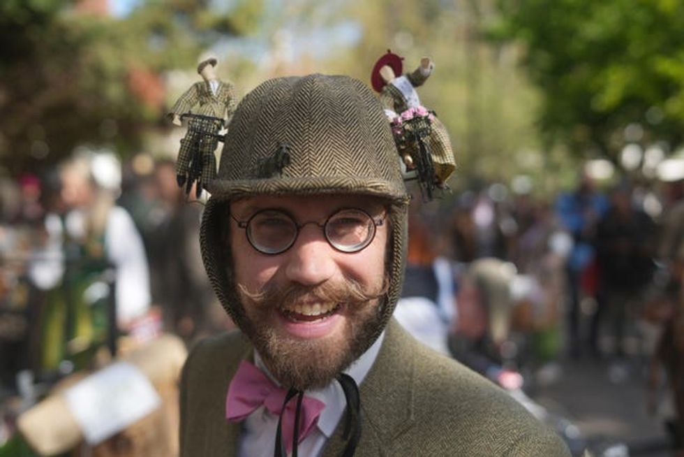 A man in a tweed cap with models of tweed cyclists on the side