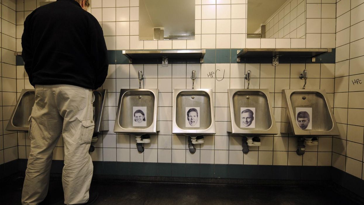 A man in central Reykjavik urinates on pictures of bankers  who left Iceland after the 2008 financial crash