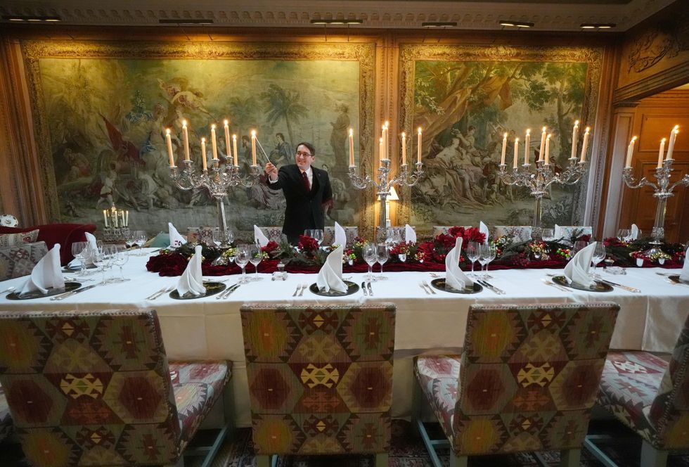 A man lights a candle on a large table set for a dinner service