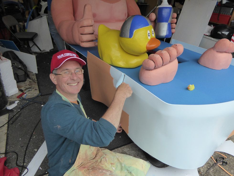 A man painting a soapbox vehicle blue