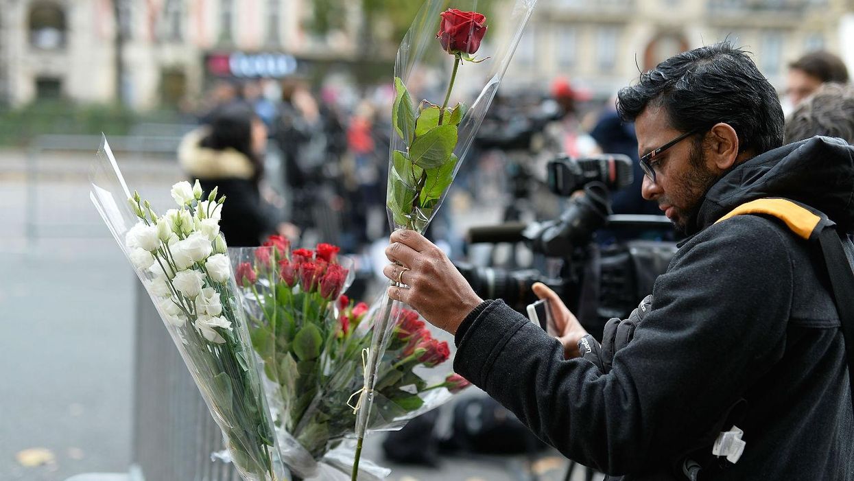 A man places a floral tribute near the Bataclan Theatre on November 14, 2015 in Paris, France