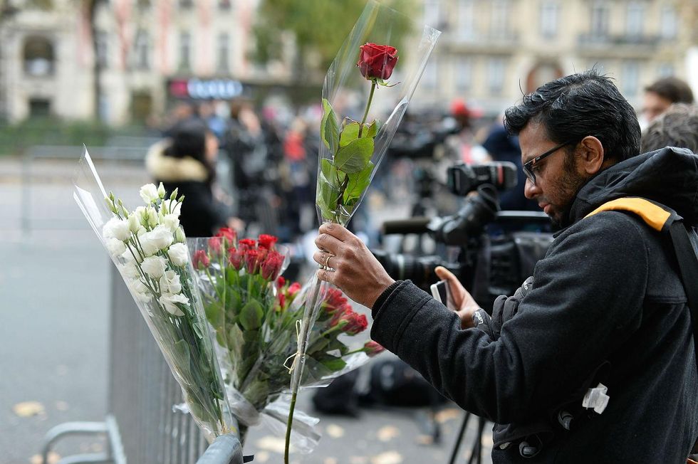 A man places a floral tribute near the Bataclan Theatre on November 14, 2015 in Paris, France