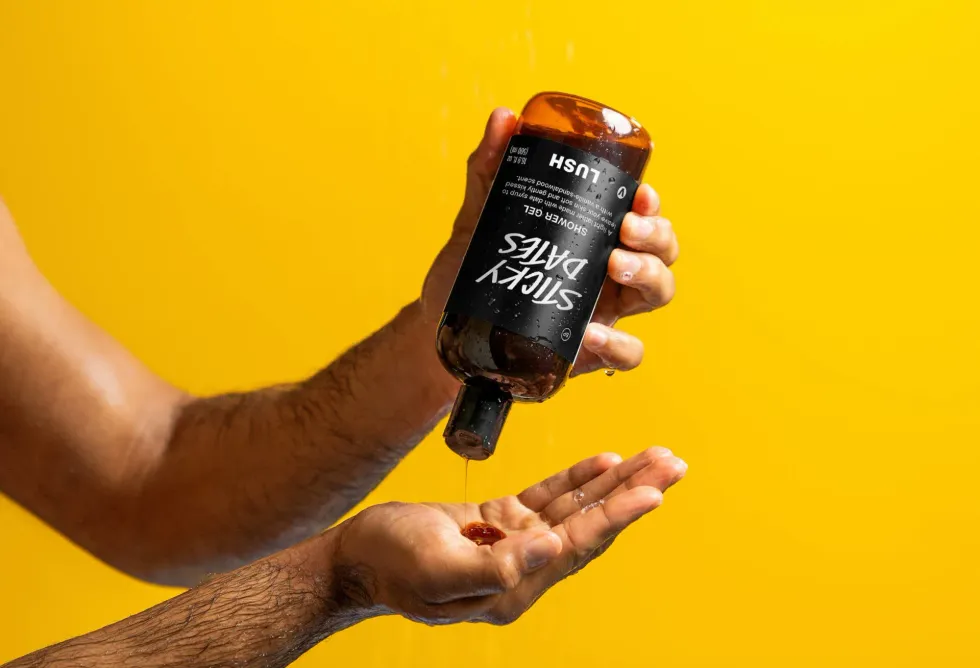 A man squeezes out shower gel from the bottle into his hand.