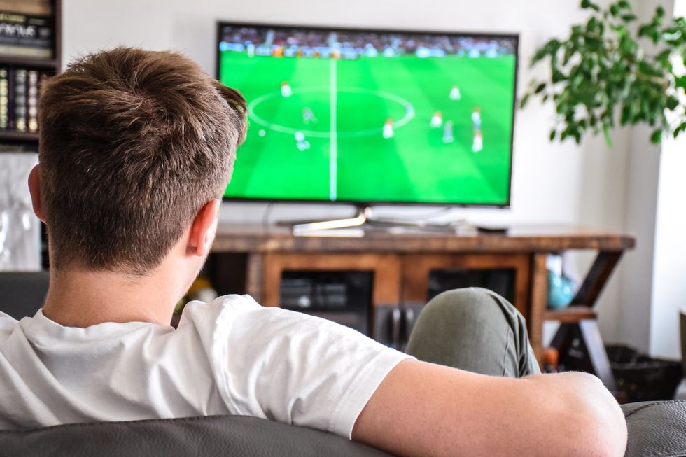 A man watches football on a television at home