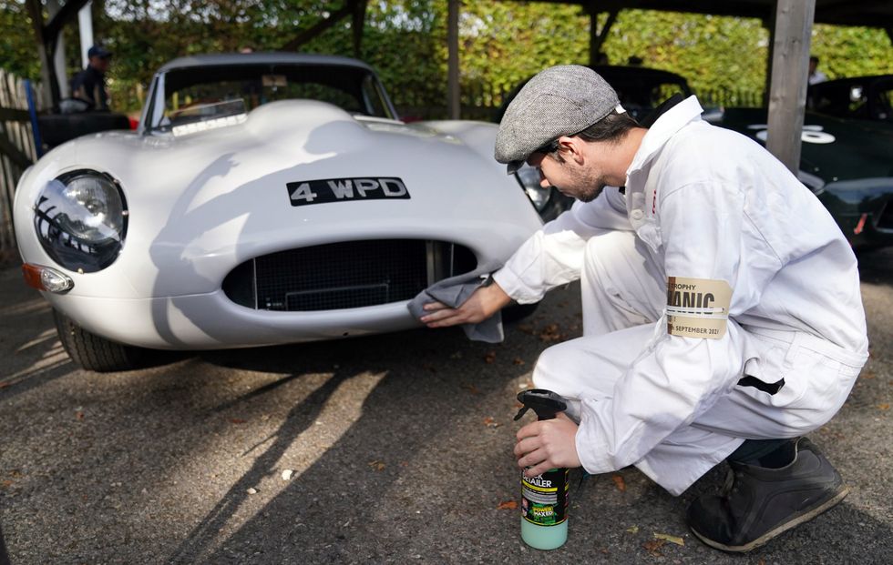 A mechanic cleans a 1961 Jaguar E-type lightweight (Andrew Matthews/PA)