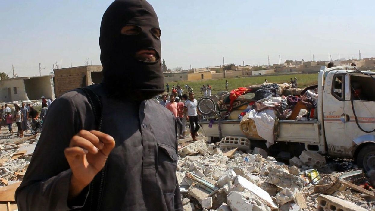 A member of the Islamic State terror group stands on rubble after an airstrike in Raqqa in September 2014.