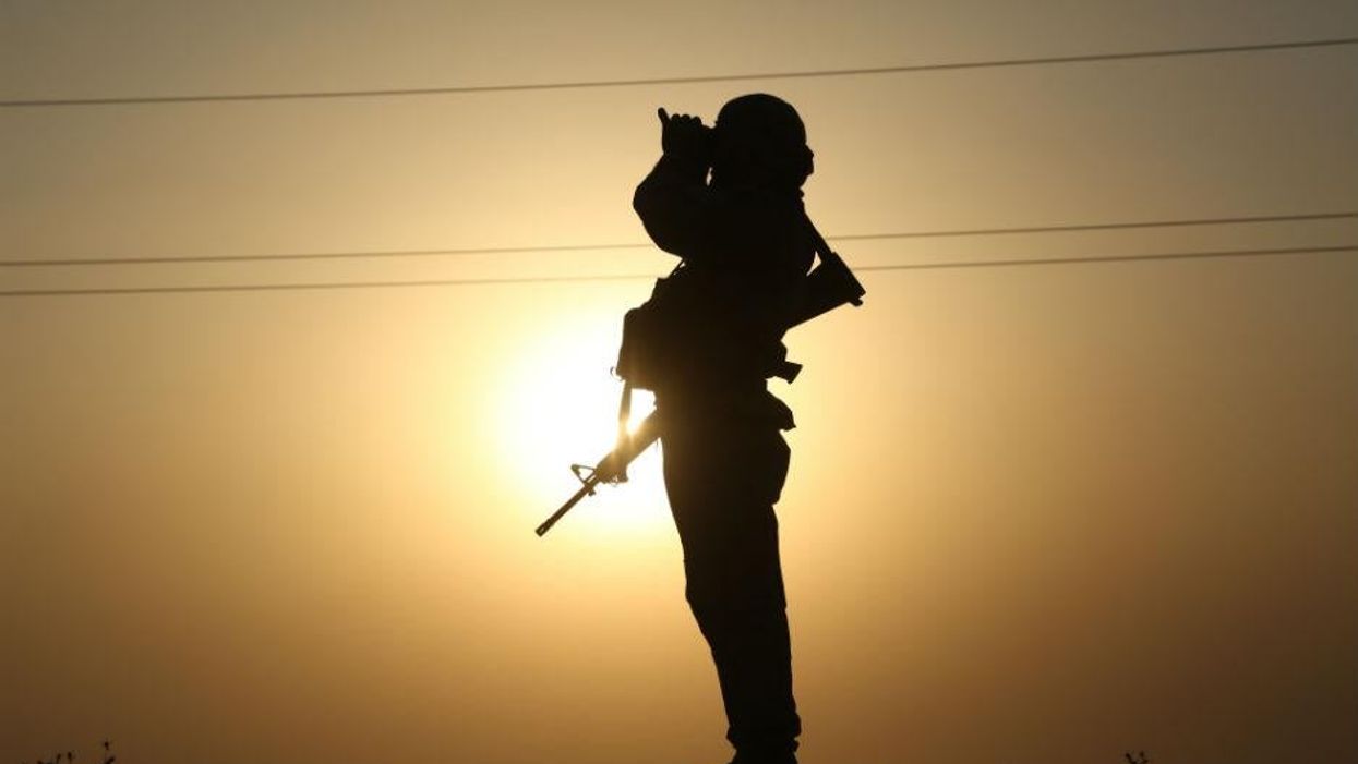 A member of the Kurdish Peshmerga looks for Isis activity through binoculars in northern Iraq