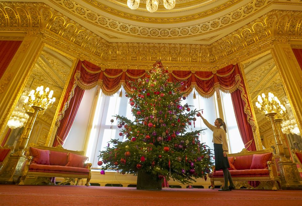 A member of the Royal Collection Trust staff decorates a Christmas tree in the castle (Steve Parsons/PA)