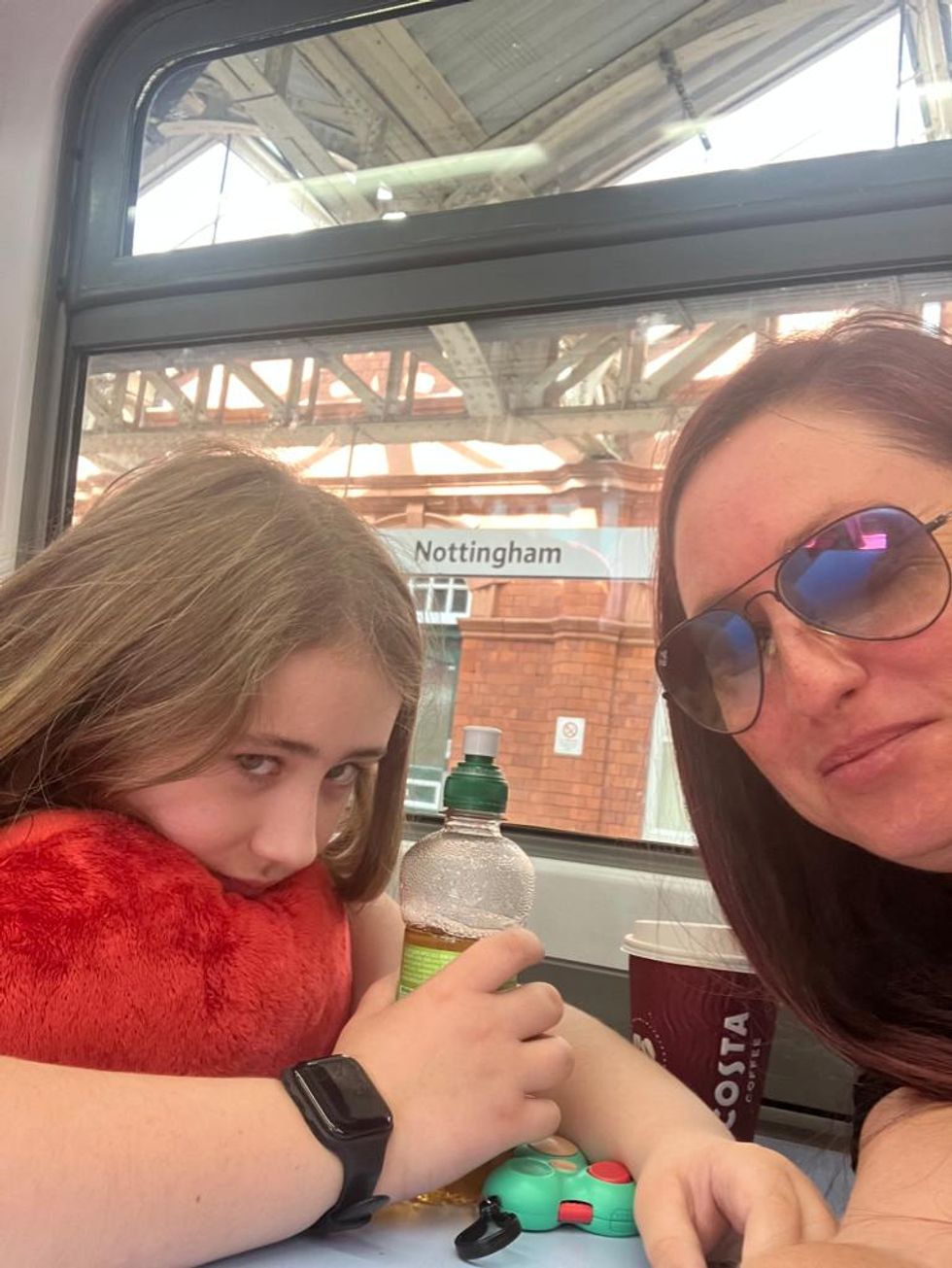 A mother and daughter take a selfie sat on a train with a Nottingham sign in the background