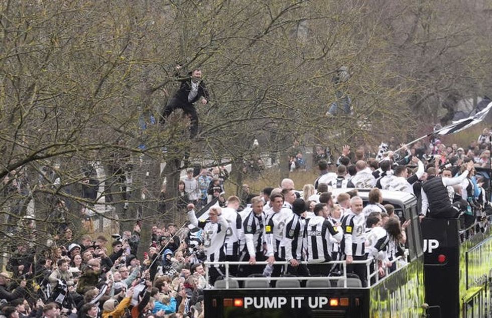 A Newcastle United fan watches on in a tree as the players pass by aboard an open top bus during the Carabao Cup trophy parade in Newcastle