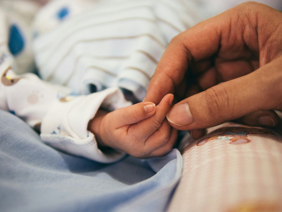 A person holding baby's index finger