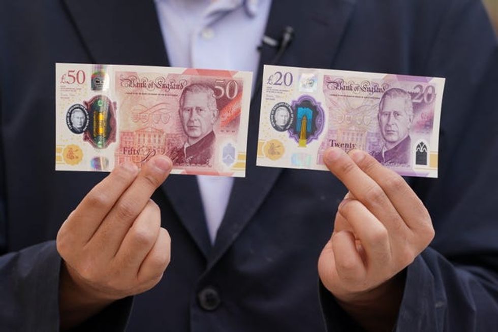A person holds some of the newly released banknotes, featuring the King\u2019s portrait, outside the Bank of England, London