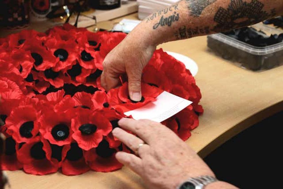 A person makes a poppy wreath