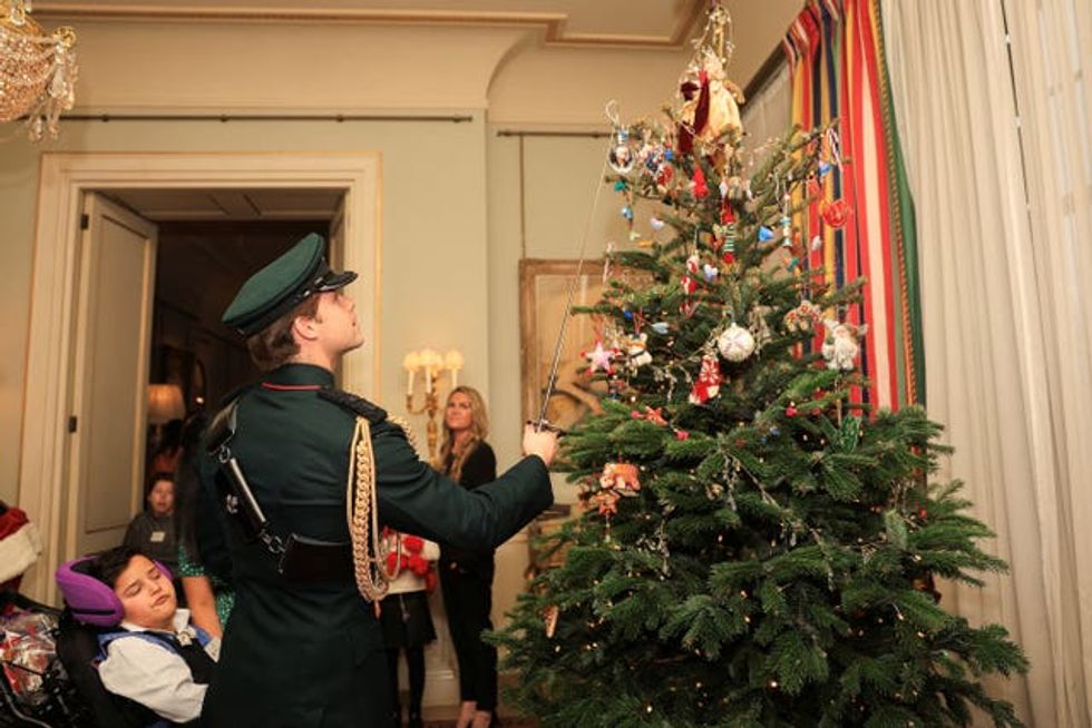 A person places a decoration on a Christmas tree