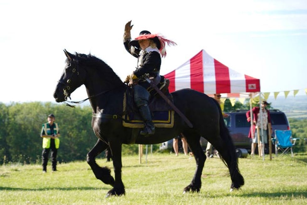 A person riding a horse in historic costume