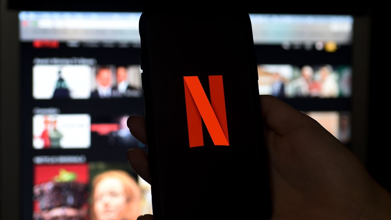 A phone is held before a TV bearing the Netflix corporate logo