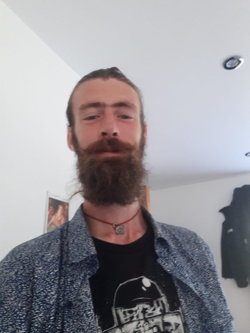 A photo of Jesse Geaney smiling at the camera wearing a blue shirt