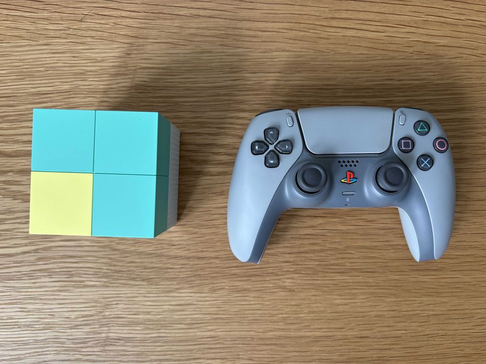 A photo of the Nex Playground console next to a DualSense wireless controller
