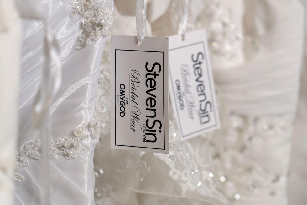 A photo zoomed in on a tag on the wedding dresses reading 'Steven Sin'