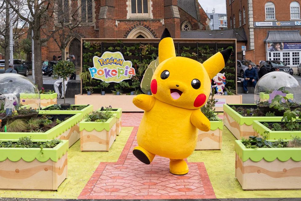 A photograph of someone in a Pikachu costume standing in front of the Pokopia Gardens in London
